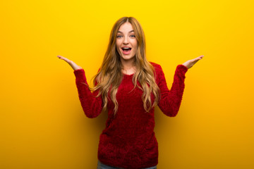 Young girl on vibrant yellow background with surprise and shocked facial expression