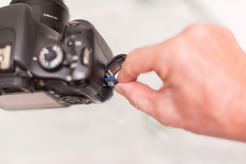 Hand insert a SD card in a black SLR Camera on white backgound 