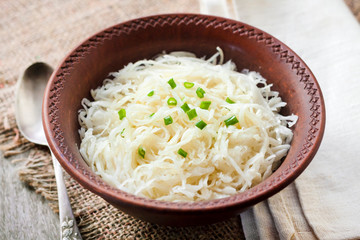 Sauerkraut with green onions in rustic bowl