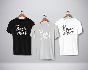 Basic Black, gray and white short sleeve T-Shirts Mock-up clothes set hanging isolated on wall. Front side view with lettering for your design or logo.