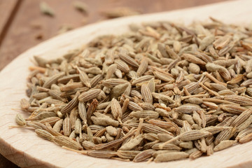 Comino en grano en una cuchara de madera sobre fondo de madera, detalle