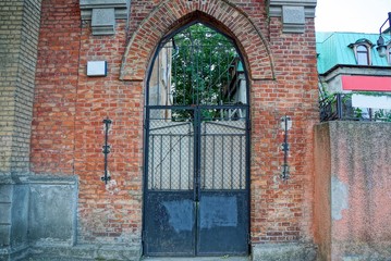 Fototapeta na wymiar old black iron gate on a brown brick building wall