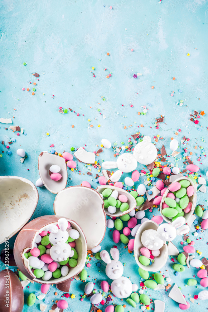 Wall mural Colorful spring easter sweets background, with chocolate eggs, sugar sprinkles and marshmallow bunny, turquoise light blue concrete background copy space top view