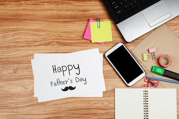 Happy Father's Day card with office supplies on wooden desk