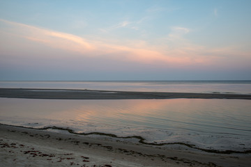 sandy sea beach with rocks and low tide in overcast day