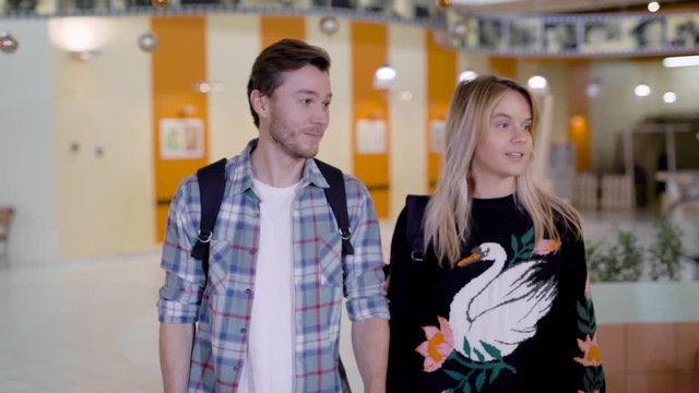 joyful young man and woman are approaching to cute hostess of a cafeteria in a food court of big mall