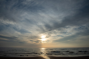 Naklejka premium dramatic high contrast clouds in sunset over seaside beach