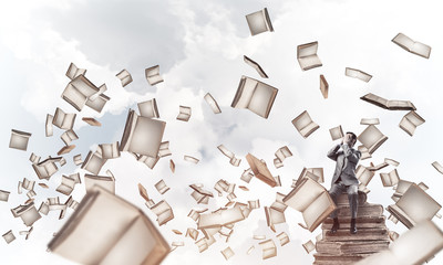 Young man sitting on books and do not want to see anything