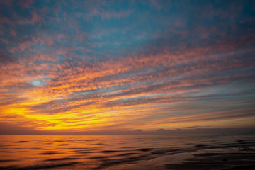 Naklejka na ściany i meble dramatic high contrast clouds in sunset over seaside beach