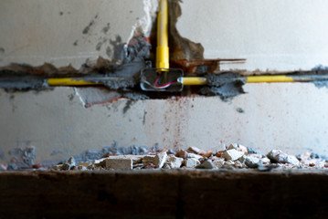 Selective focus picture of crushed concrete lump with blurred broken plastered cement wall in background