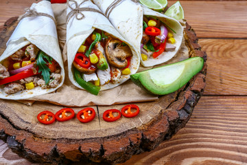 Chicken caesar salad wraps with bacon, avocado beans, tomatoes, lettuce and cheese. Tortilla, burritos, sandwiches twisted rolls