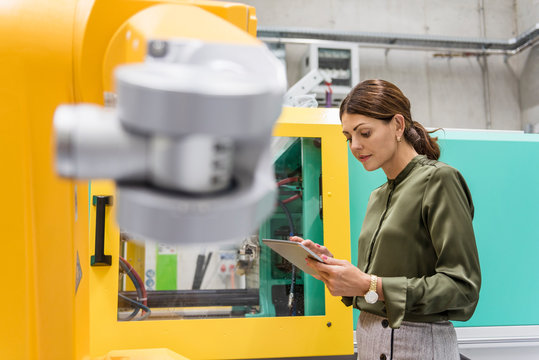 Businesswoman checking industrial robot in high tech company