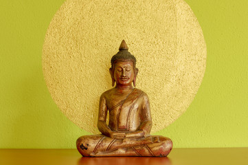 Buddha im Lotussitz vor grüner Wand