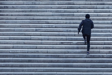  Athletic young man runs up the stairs. - obrazy, fototapety, plakaty