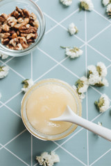 Walnuts, honey and white flowers on table