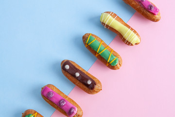 Closeup of diagonal row of colorful decorated French eclairs with copy space