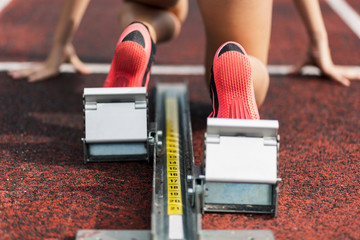 Teenage runner kneeling on starting block, close up