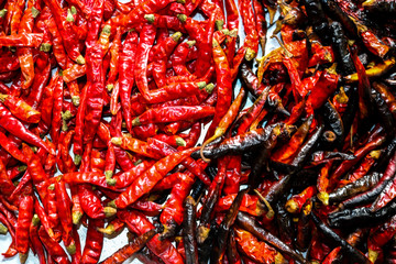 Red and black chillies are placed side by side in a large, hot and spicy chill.