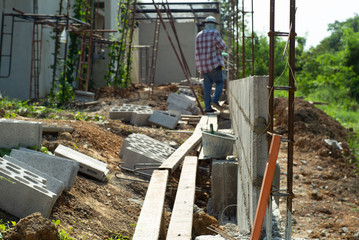 Selective focus of reinforcement steel and cement bricks wall with blurred workers in background at the construction site