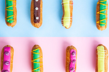 Closeup of colorful decorated eclairs on pink-blue background