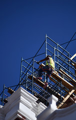 A worker on a church construction site in Mexico. A worker with a safety vest on a scaffolding.