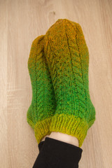 A woman wearing warm hand craft socks. Knitted from a natural sheep wool yarn. Winter clothing. On a wooden background.
