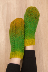 A woman wearing warm hand craft socks. Knitted from a natural sheep wool yarn. Winter clothing. On a wooden background.