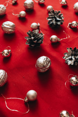 Flat lay of silver balls and pine cones on red background, Christmas pattern
