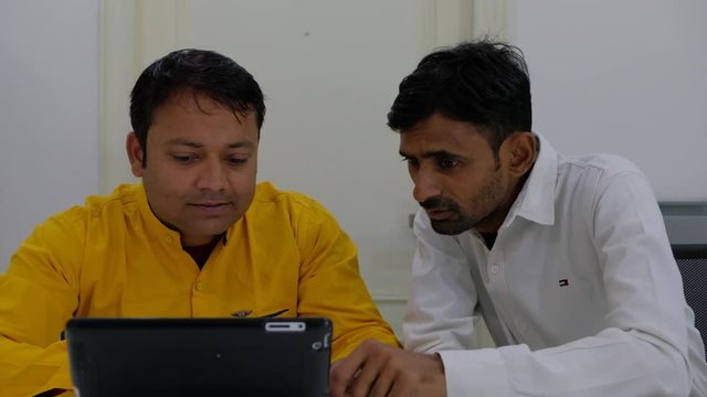 Two shot of senior colleague berates his junior in office seriously, who animatedly regrets and apologies 