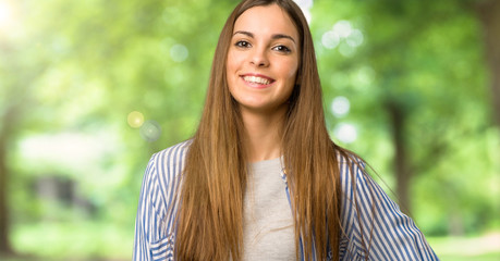 Young girl with striped shirt posing with arms at hip and smiling at outdoors