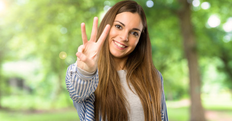 Young girl with striped shirt happy and counting three with fingers at outdoors