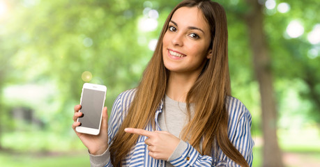 Young girl with striped shirt showing the mobile at outdoors