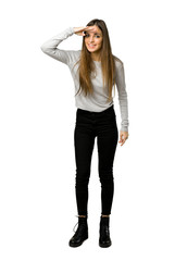 Full-length shot of young girl looking far away with hand to look something on isolated white background