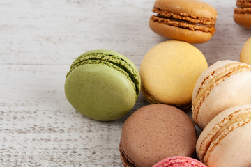Pile of colorful French macarons on white rustic wooden table
