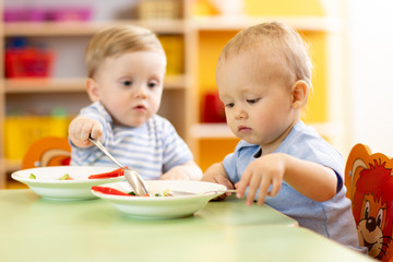 babies children eating healthy food in nursery or kindergarten