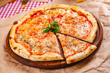 Italian Pizza Margherita with tomatoes and mozzarella cheese on wooden cutting board. Close up