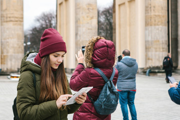 A beautiful tourist girl uses a tablet in the square next to the Brandenburg Gate in Berlin. Nearby...