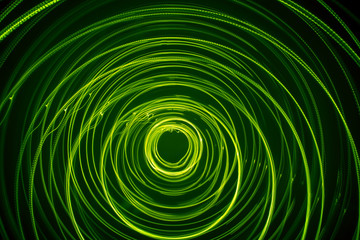 A beautiful, bright light swirl of green color. Futuristic light painting on a black background....