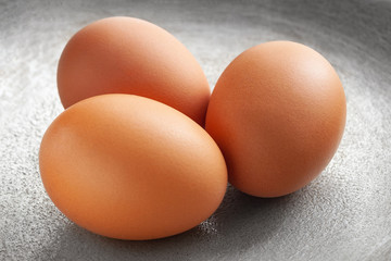 brown eggs on the background of a metal pan.