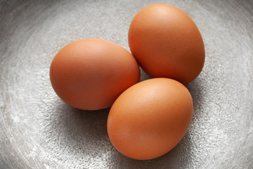 brown eggs on the background of a metal pan.