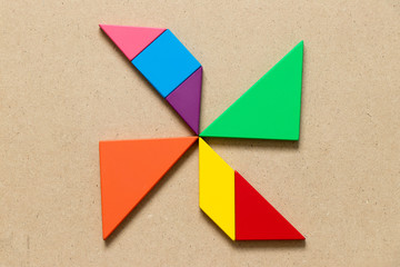 Color tangram puzzle in wind turbine shape on wood background