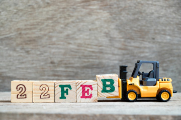 Toy forklift hold block B to complete word 22feb on wood background (Concept for calendar date 22...