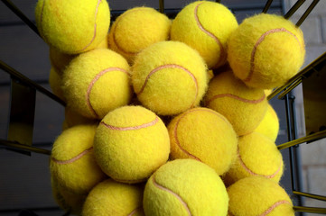 close up view of yellow tennis balls in basket