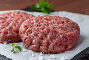 Raw burger patties on white paper, raw minced pork.