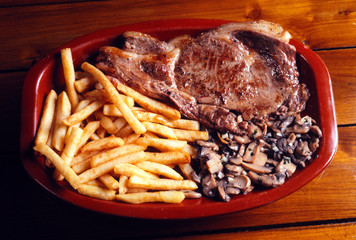 Bandeja con una chuleta de ternera con patatas fritas y champiñones