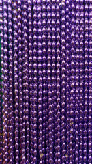 Many purple beads party neacklaces for celebrations or background. Macro close up vertical
