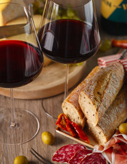 red wine in glasses, cheese, baguette, sun-dried tomatoes and olives. Composition.