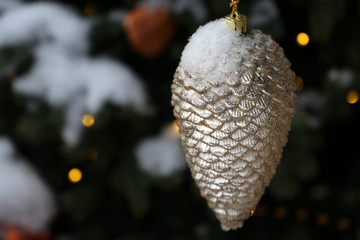 New Year toy pine cone covered with snow, magic of the holiday. Christmas decoration on fir branches in winter night