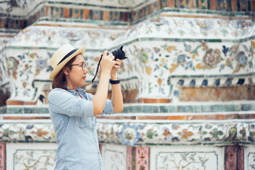 Fototapeta premium Beautiful woman tourist Held camera to capture the memories. Wat Arun Temple in Thailand. using as background travel concept with copy spaces for your