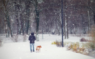Fototapeta na wymiar Young man walking in the winter park in snowfall